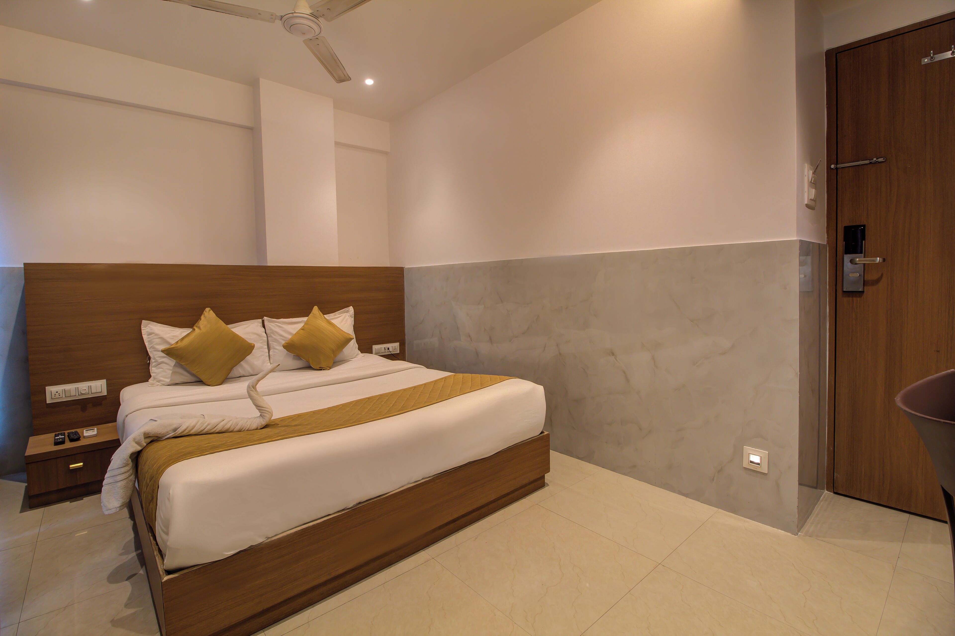 Habitación de hotel moderna con una cama grande, cabecera de madera y una pared de acento de mármol gris.