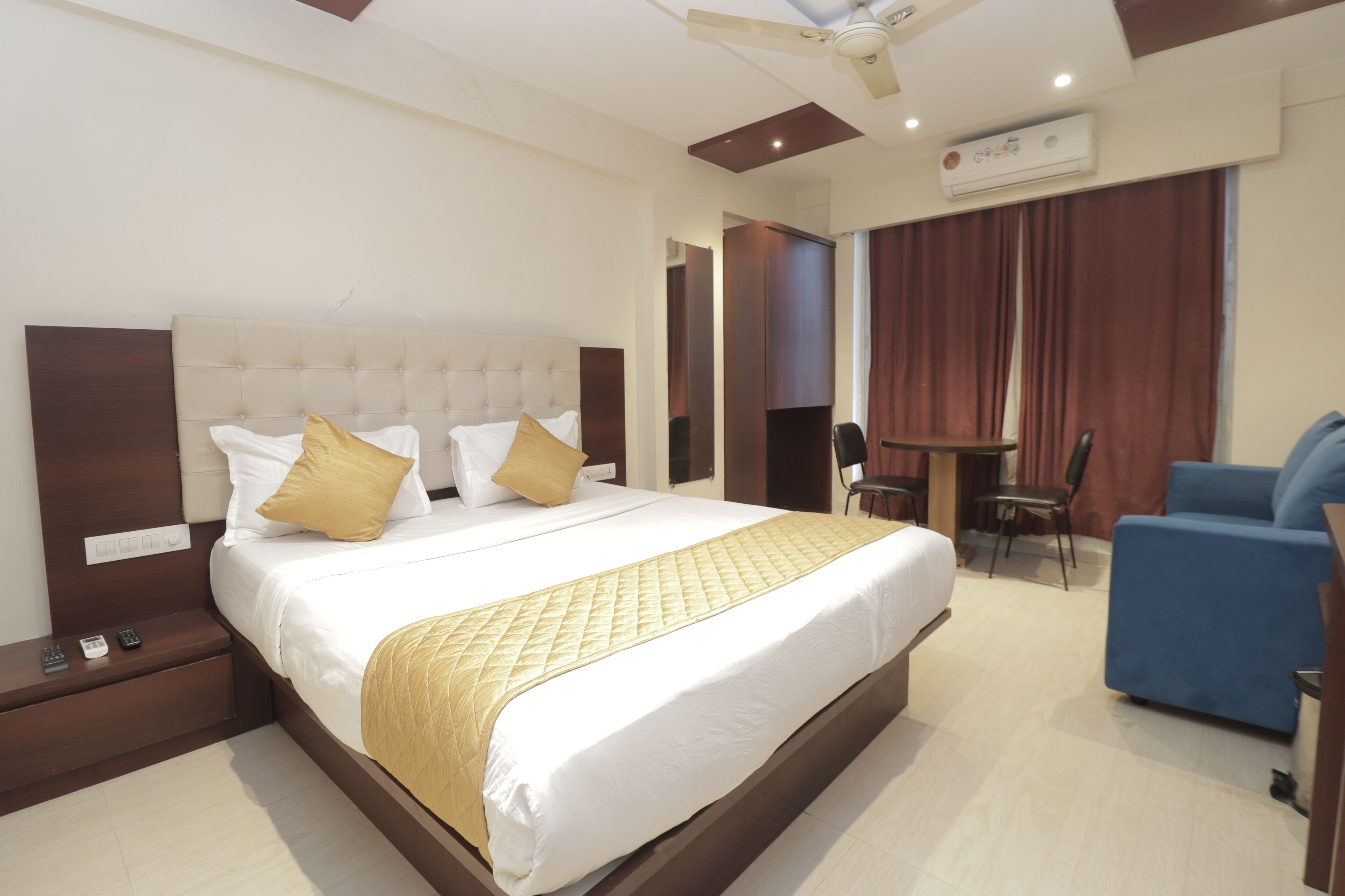 A hotel room with a large bed, a desk, a chair, and a blue sofa.