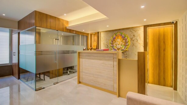 A reception area with a glass partition, a wooden reception desk, and a decorative wall piece. - Hotel Malad Inn (Mumbai)