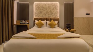 A hotel room with a large bed, a bedside table with a lamp, and a wall-mounted phone. - Hotel Malad Inn (Mumbai)