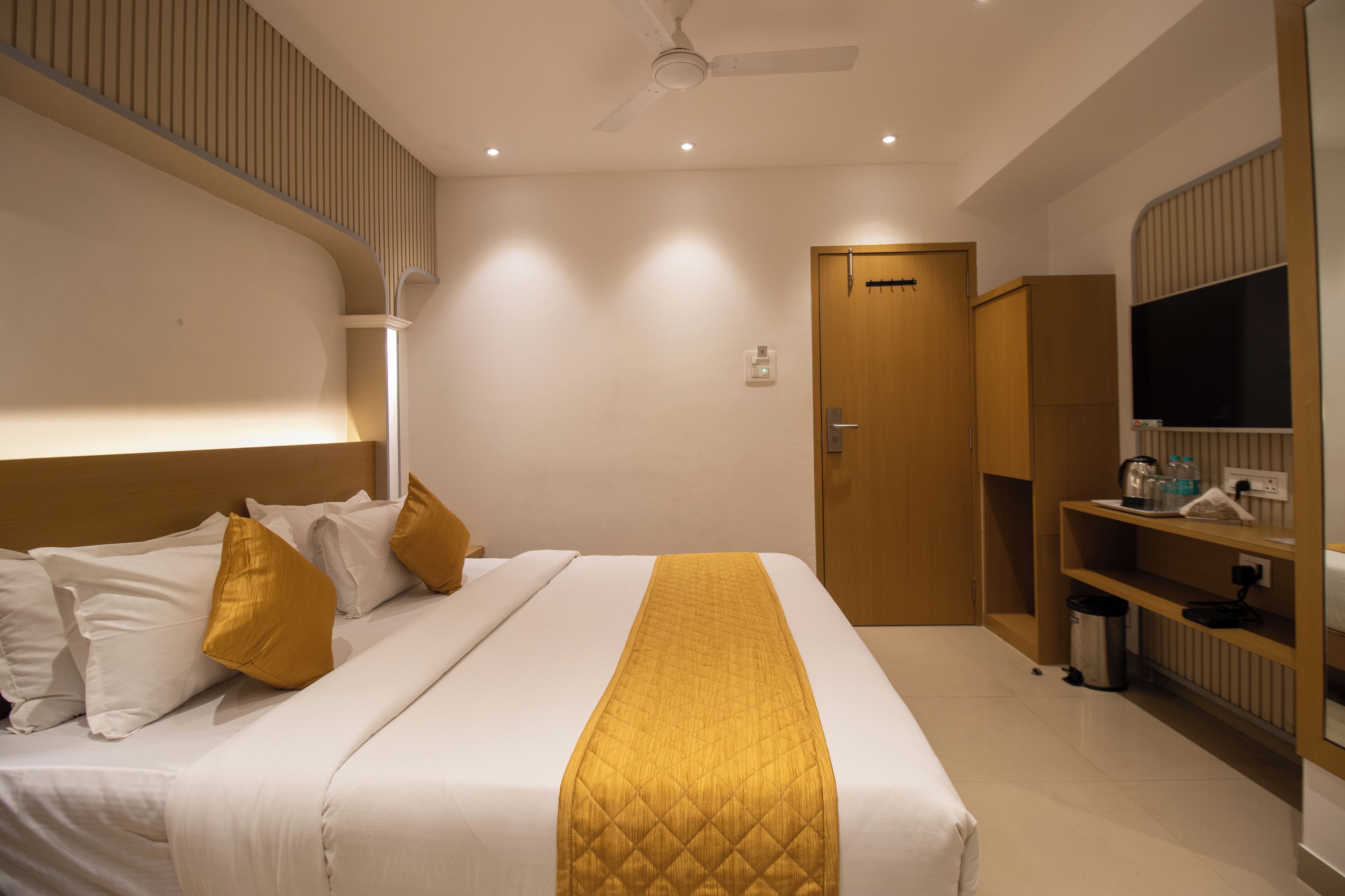 A modern hotel room with a neatly made bed, a television, and a wardrobe.