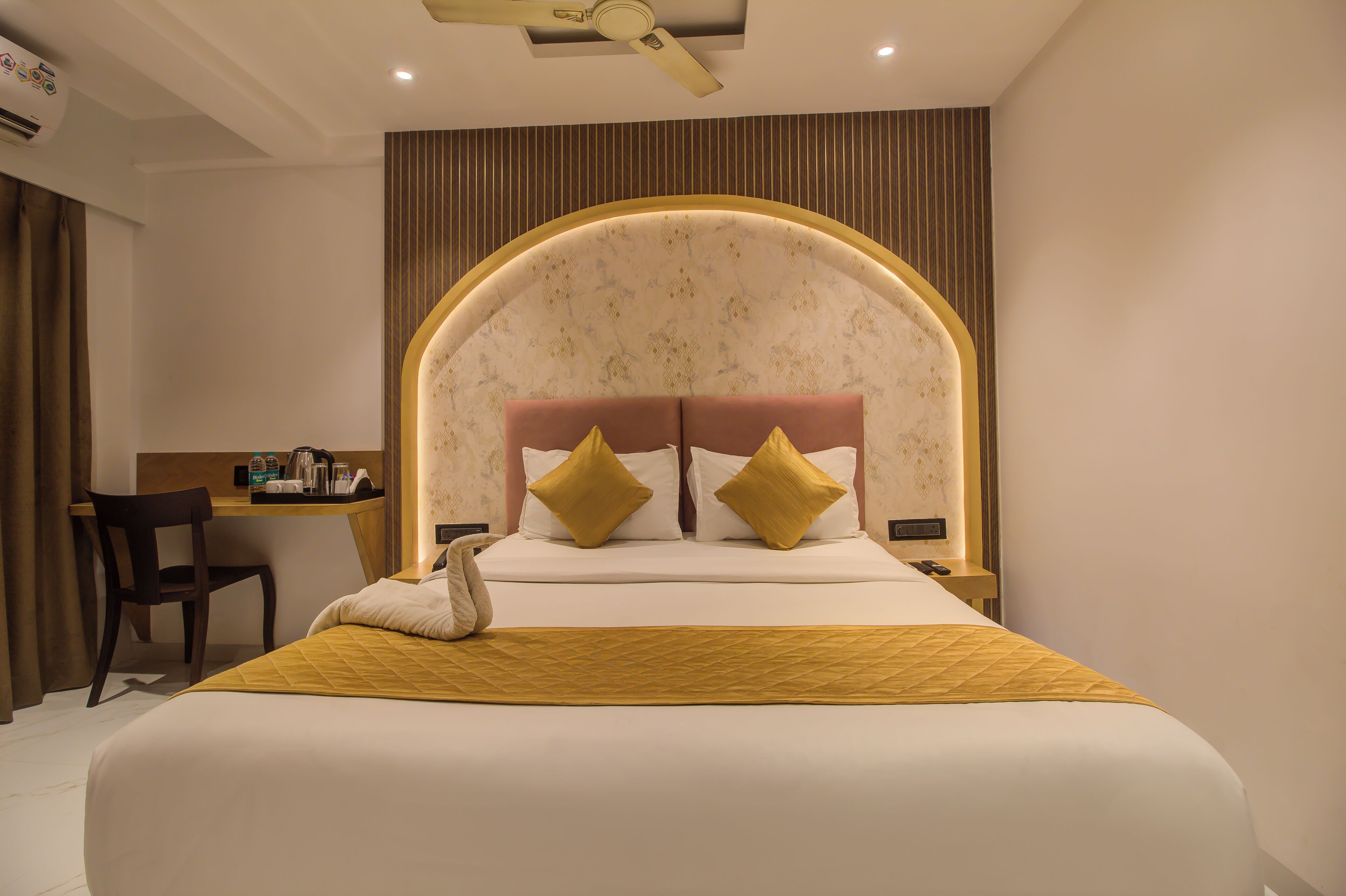 A hotel room with a large bed, a desk, and a chair.