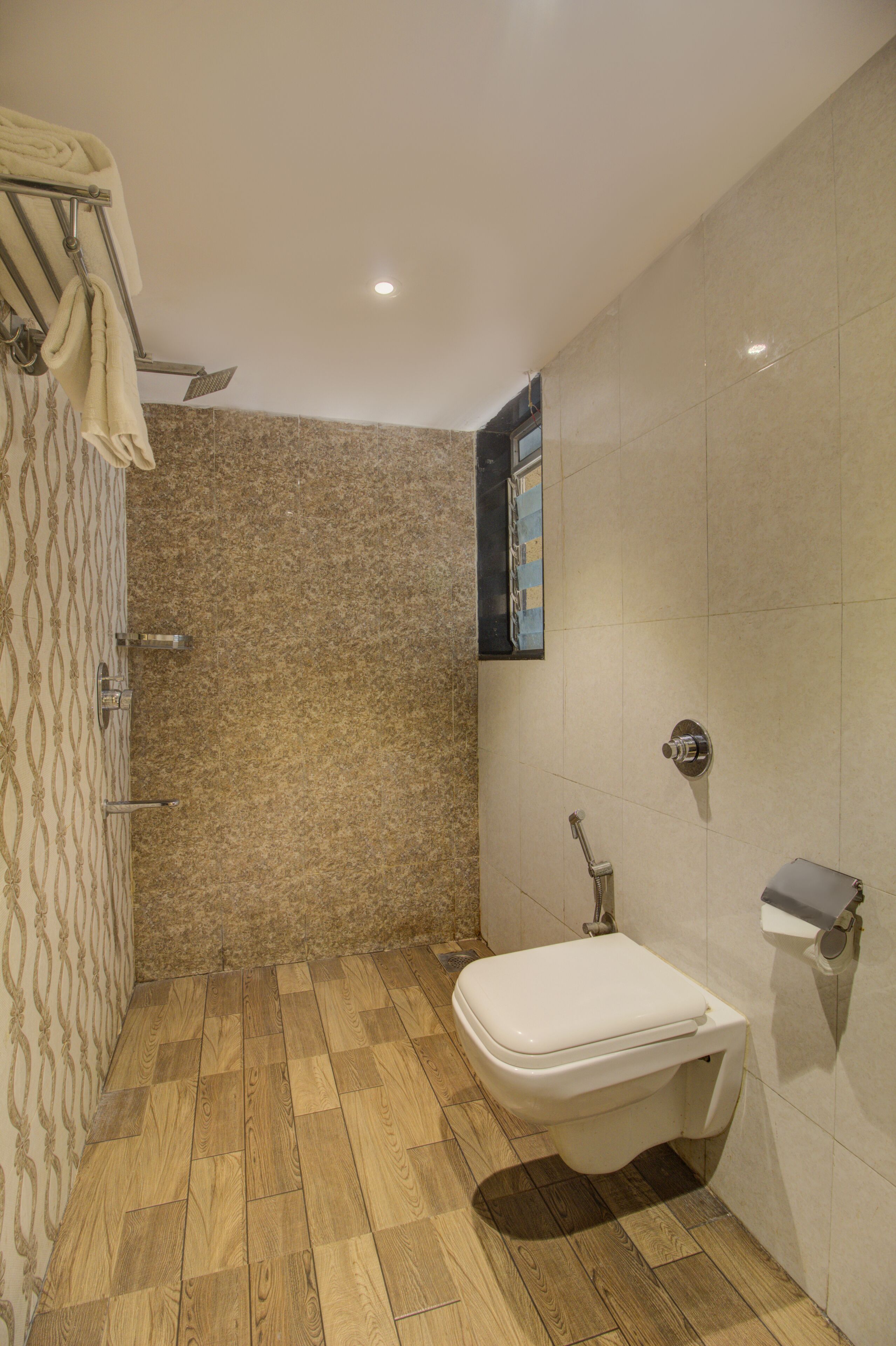 A bathroom with a shower, toilet, and a towel rack.