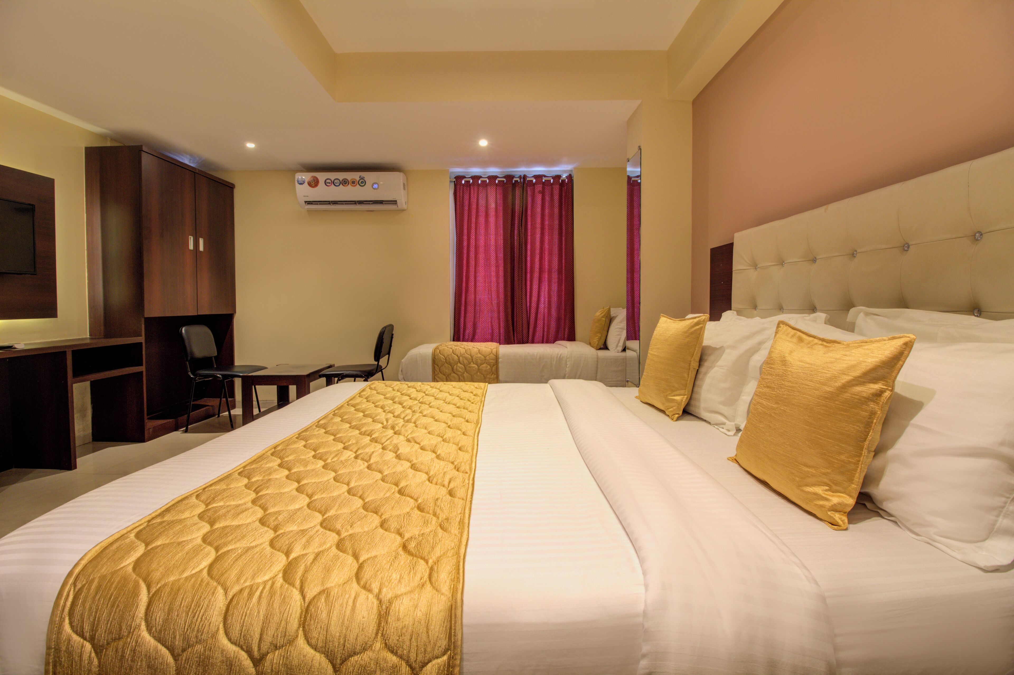 A hotel room with a large bed, a desk, a chair, and a television.