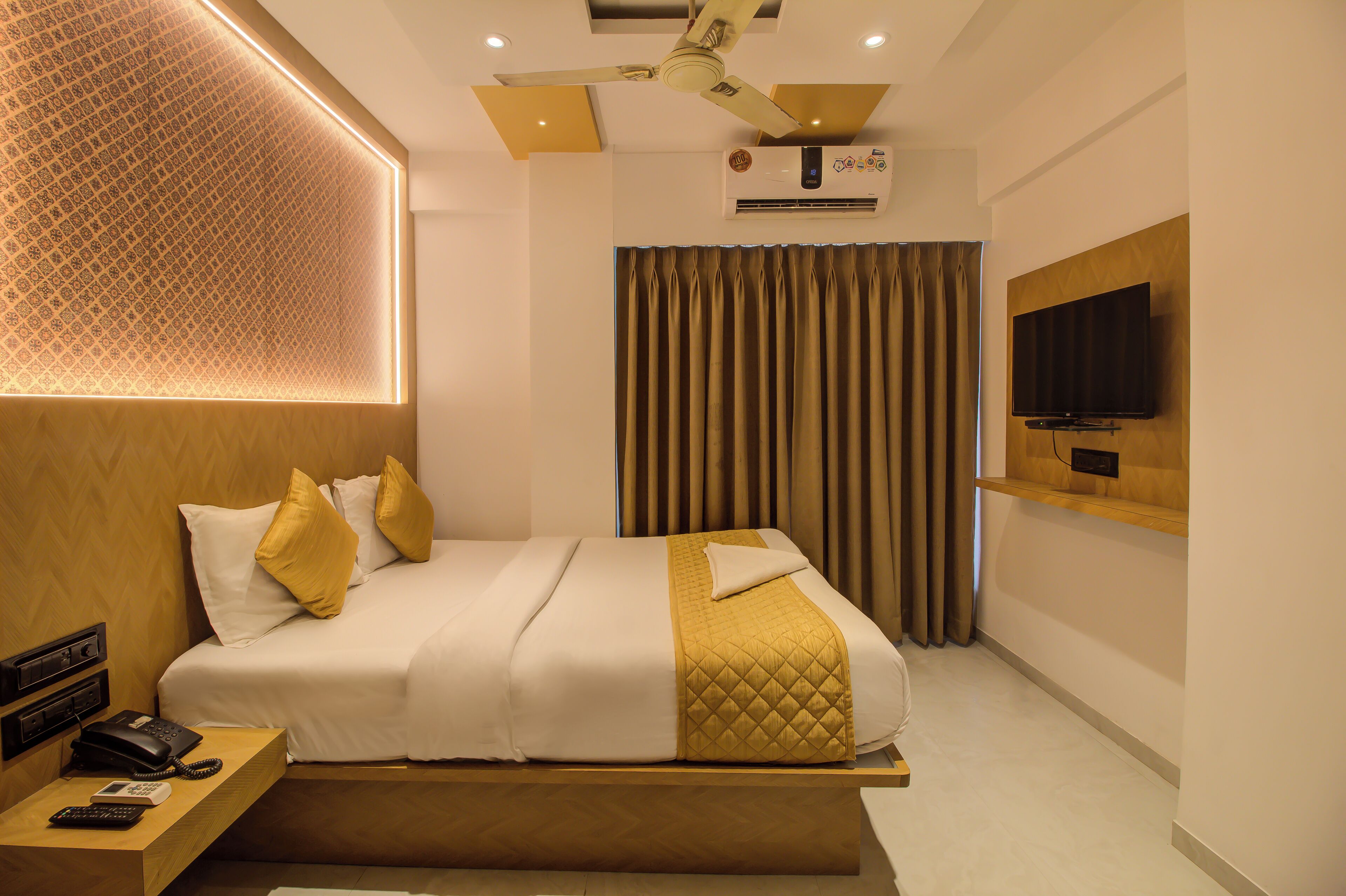 A modern hotel room with a bed, bedside table, and a mounted TV.