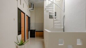 Un interior moderno con una escalera en espiral, una planta en maceta y una zona de cocina.