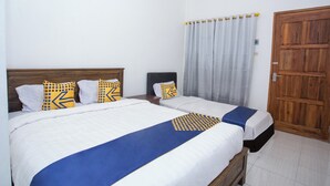 A hotel room with two beds, a wooden wardrobe, and a window with curtains. - Hotel O Pondok Kartini (Jepara)