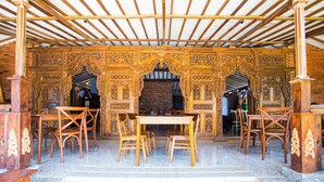 An ornate wooden structure with a table and chairs, a brick wall, and a staircase leading up. - Hotel O Pondok Kartini (Jepara)