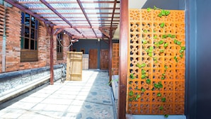 A covered outdoor area with a brick building, wooden doors, and a decorative orange lattice. - Hotel O Pondok Kartini (Jepara)