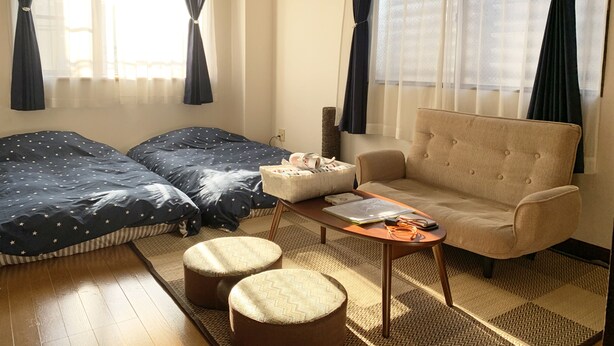 Una habitación con cama, sofá, mesa de centro y ventana con cortinas.