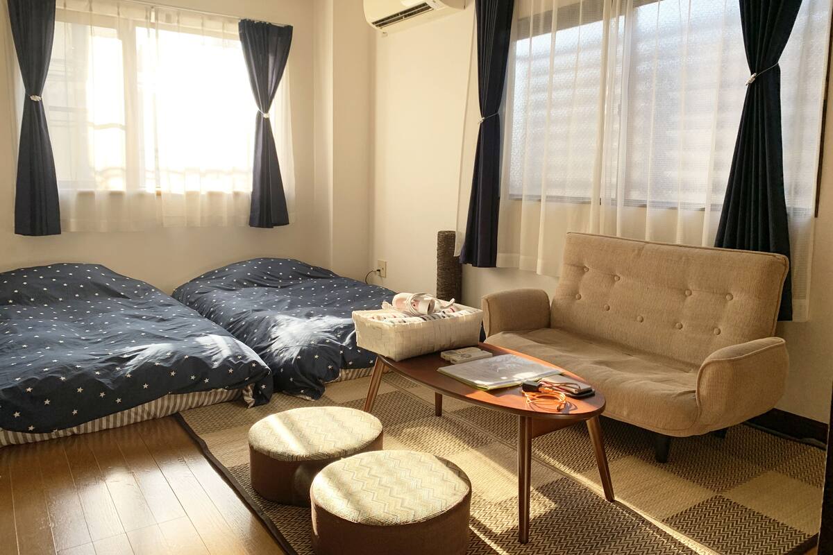 Una habitación con cama, sofá, mesa de centro y ventana con cortinas.