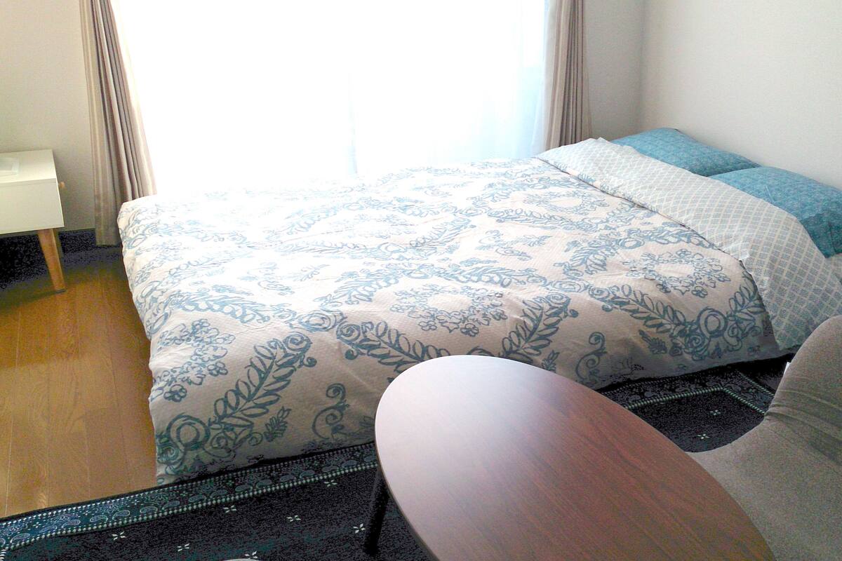 Un dormitorio con una cama, una silla y una mesita.
