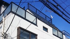 Un edificio residencial de varios pisos con fachada blanca, múltiples ventanas y un balcón.
