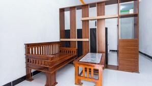 A room with a wooden bench, a small table, and a wardrobe with mirrored doors. - Hotel O Griya Annisa (Tegal)