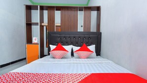 A bed with a black headboard, two red and white patterned pillows, and a red and white patterned bedspread. - Hotel O Griya Annisa (Tegal)