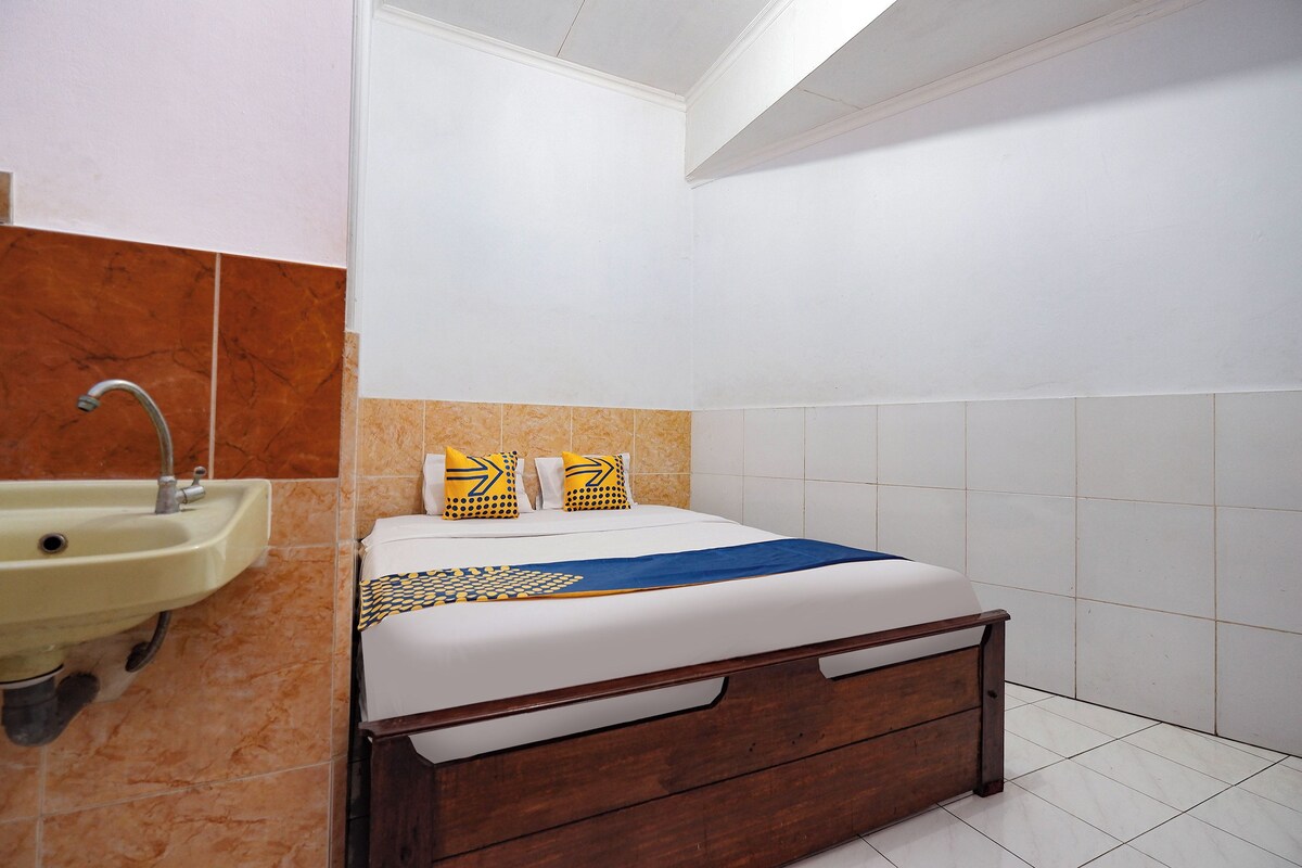 A bedroom with a wooden bed, a white wall, a sink, and orange-tiled walls.