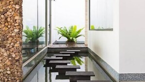 Ein modernes Innenbrunnen mit Steinwand, Glasverkleidung und Blumentöpfen.