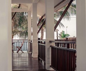 A covered outdoor area with wooden flooring, metal railings, and palm trees. - Vivian Hotel Mui Ne (Mui Ne)