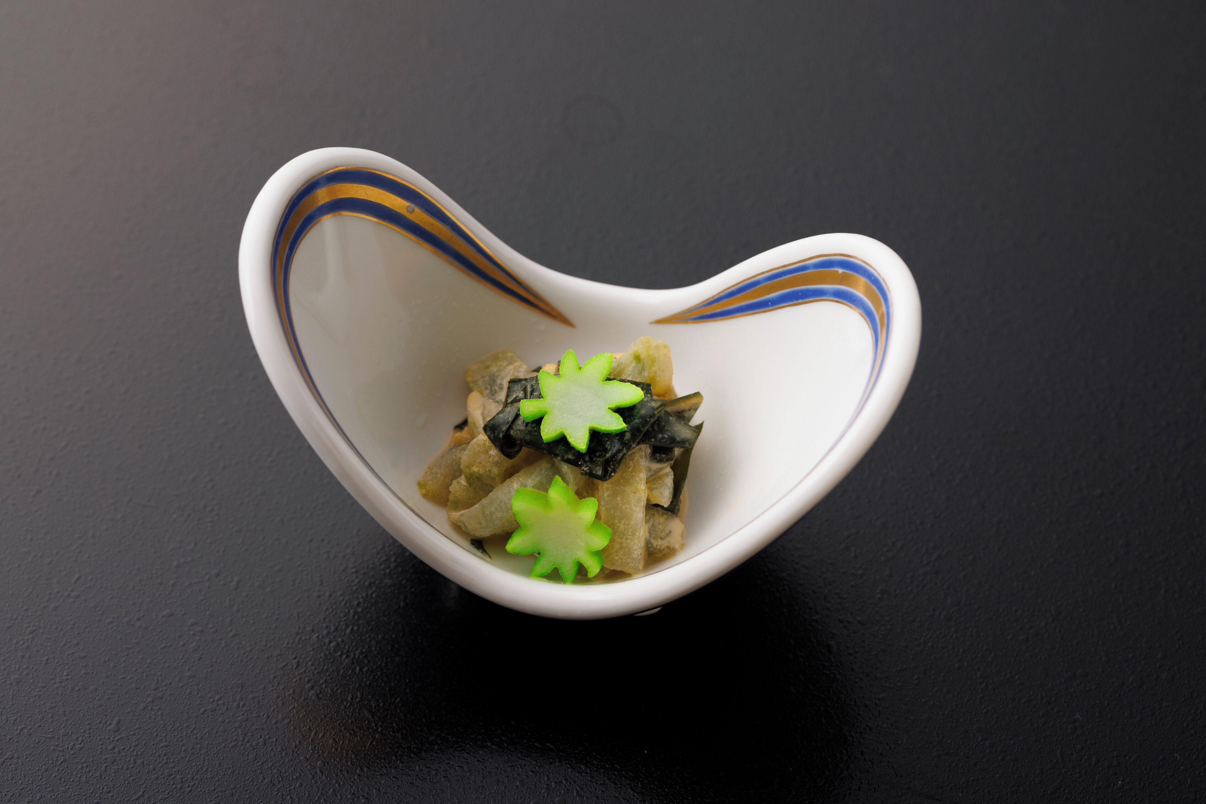 A white bowl with blue and yellow stripes on a black surface.