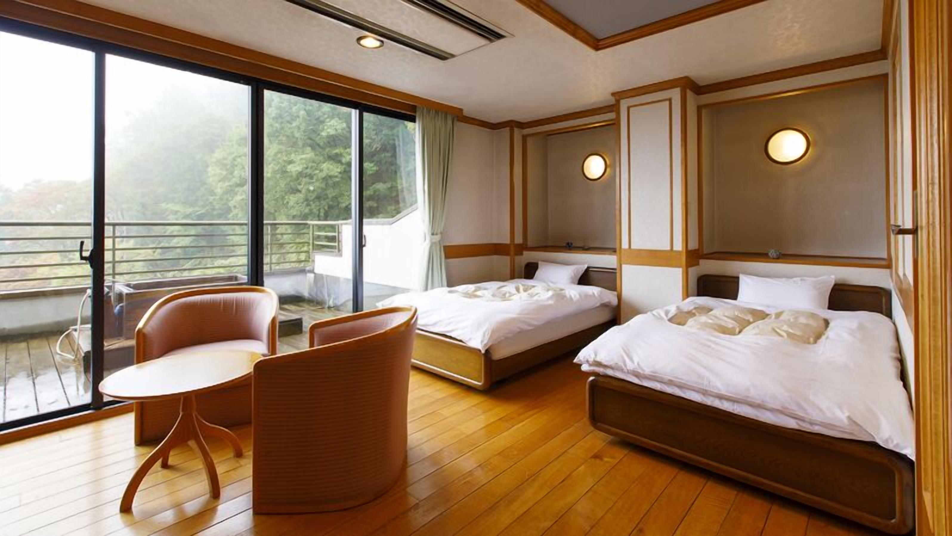 Une chambre d’hôtel avec deux lits, un balcon et un coin salon.