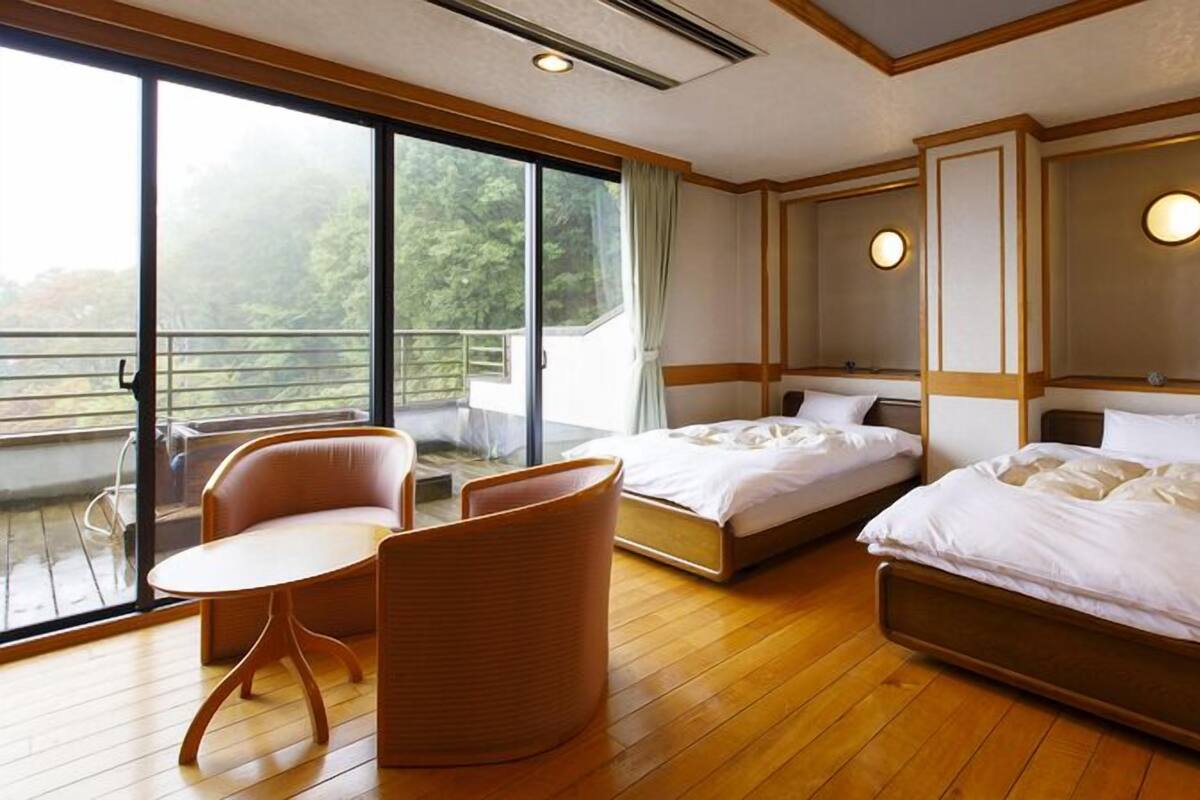 Habitación de hotel con dos camas, un balcón y zona de estar.