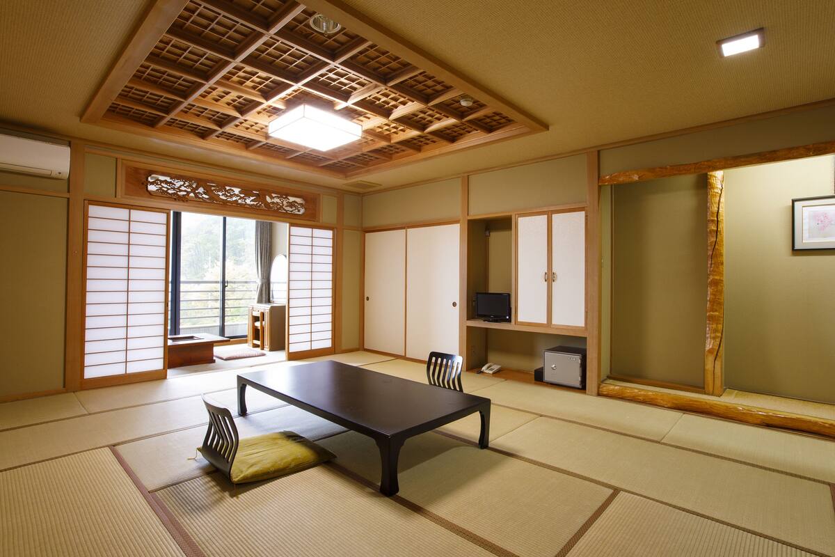Una habitación tradicional japonesa con suelo de tatami, una mesa baja y puertas correderas.