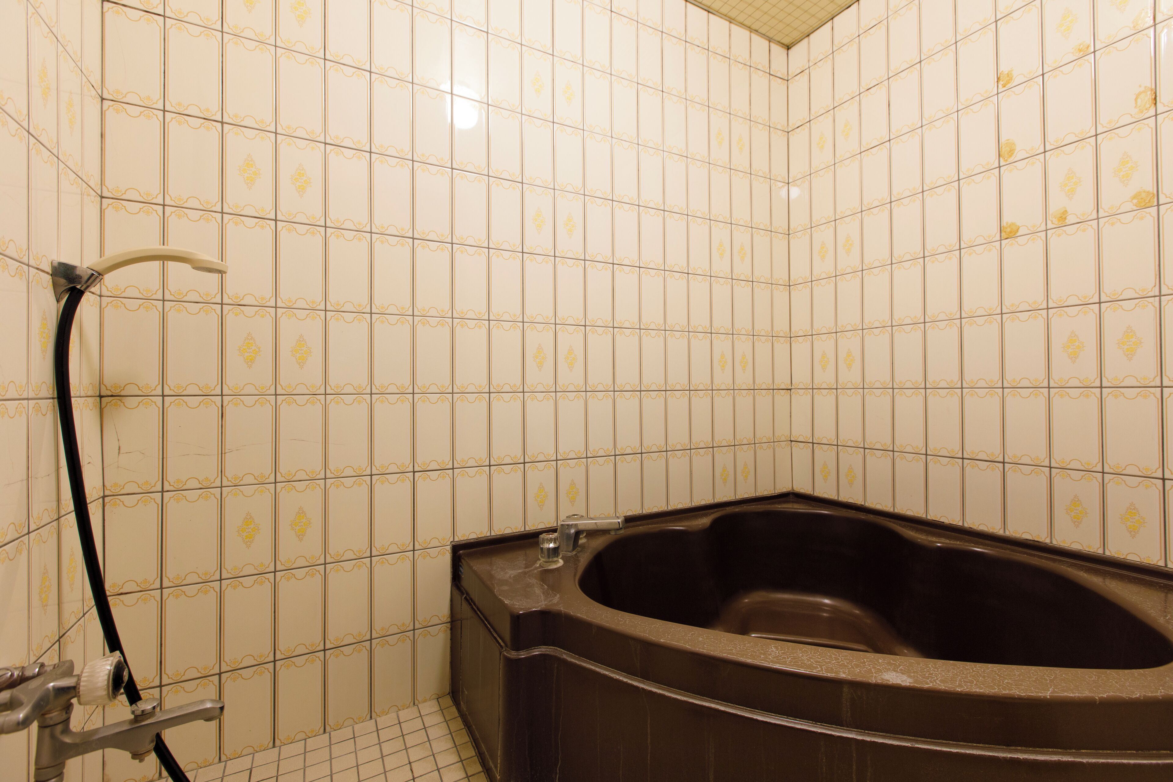 A bathroom with a large bathtub, tiled walls, and a showerhead.