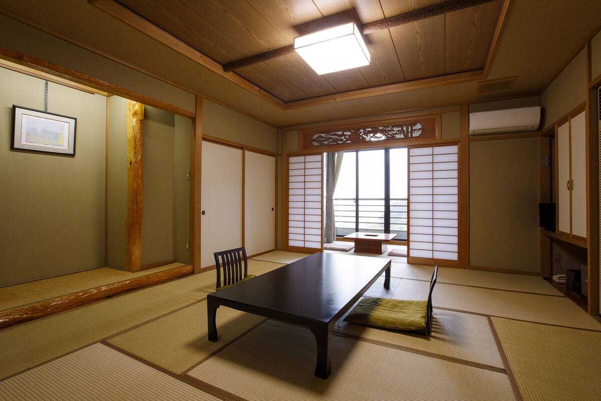 Una habitación japonesa tradicional con suelo de tatami, una mesa baja y puertas correderas.