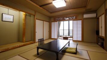 Ein traditioneller japanischer Raum mit Tatami-Böden, einem niedrigen Tisch und verschiebbaren Türen.