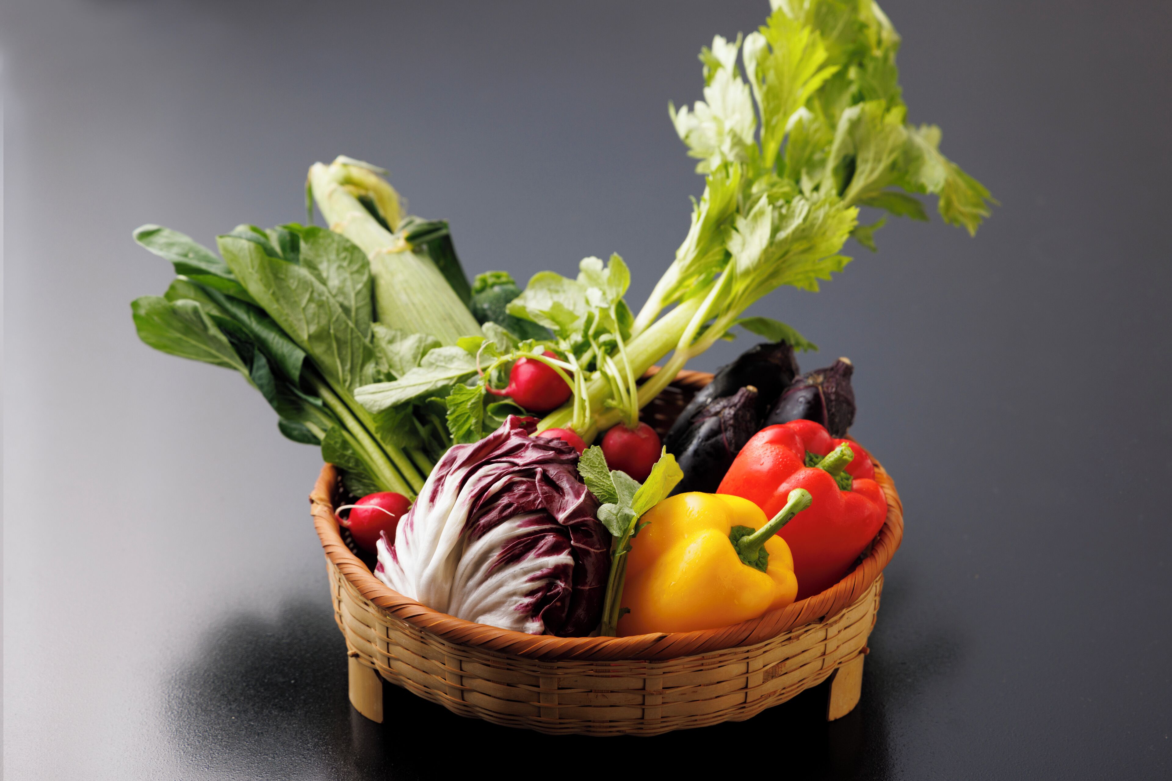 A basket of fresh vegetables including lettuce, radishes, and bell peppers.