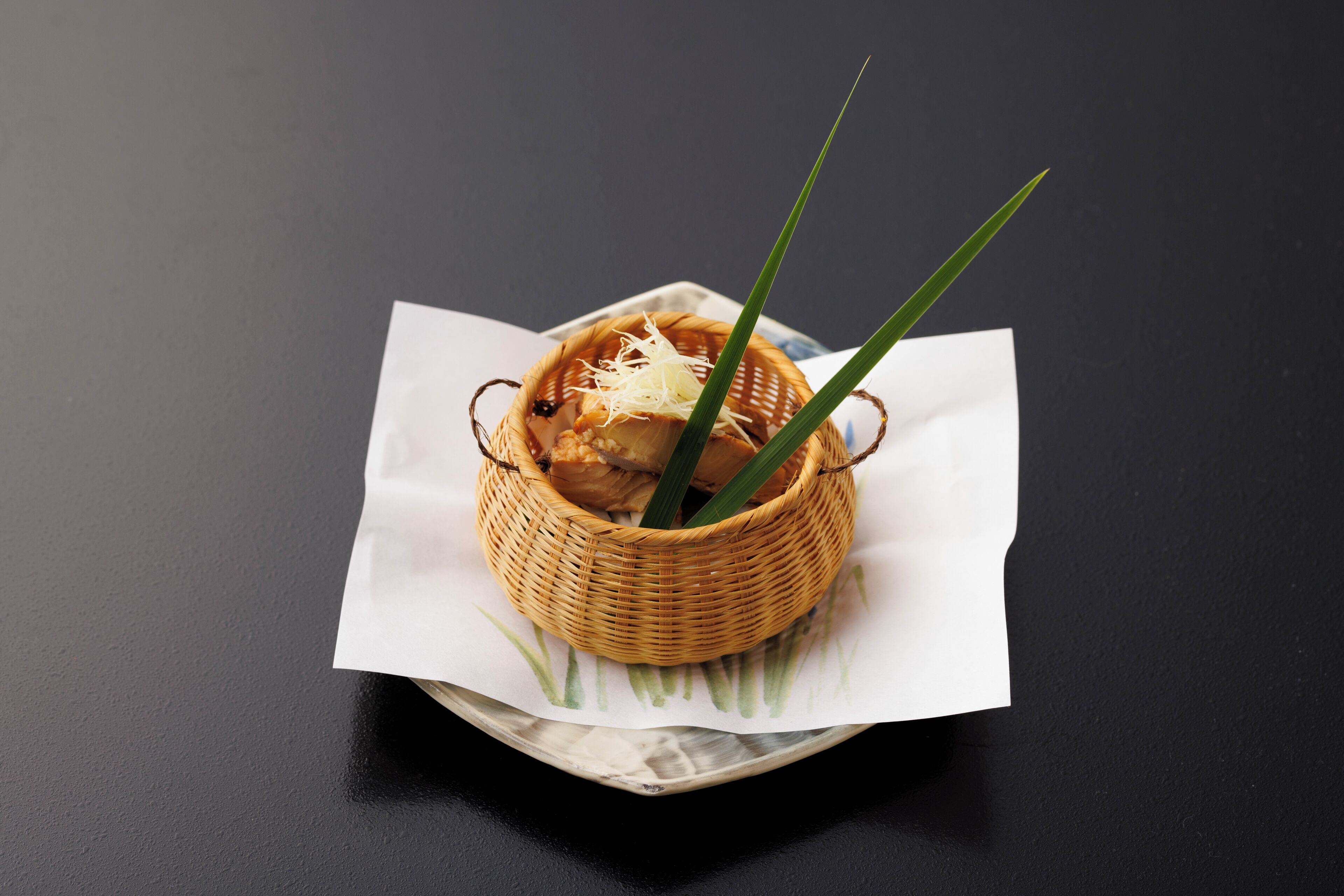 A wicker basket with a white napkin on a dark surface.