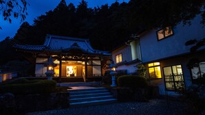 A traditional Japanese building with a tiled roof, a wooden entrance, and a stone lantern. - Temple Hotel Habanobo (Minobu)