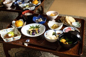A traditional Japanese meal set on a wooden tray with various dishes including sushi, pickled vegetables, and a bowl of soup. - Temple Hotel Habanobo (Minobu)