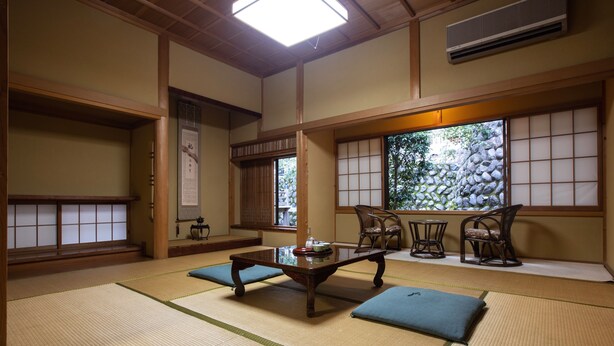 A traditional Japanese room with tatami flooring, a low wooden table, and sliding shoji doors. - Temple Hotel Habanobo (Minobu)