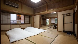 A traditional Japanese room with tatami flooring, a futon bed, sliding doors, and a view through a window. - Temple Hotel Habanobo (Minobu)