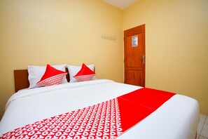A hotel room with a bed, two pillows, a red and white bedspread, and a wooden door. - Hotel O Az Zahra Residence Syariah (Surabaya)