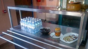 A buffet area with bottled water, a bowl of fruit, and a plate of pastries.