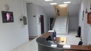 A reception area with a curved desk, a clock, and a staircase leading to an upper floor.