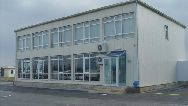 A two-story building with large windows and a blue awning.