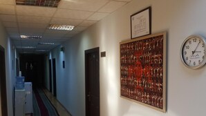 A hallway with a water dispenser, a clock, and a framed certificate on the wall.