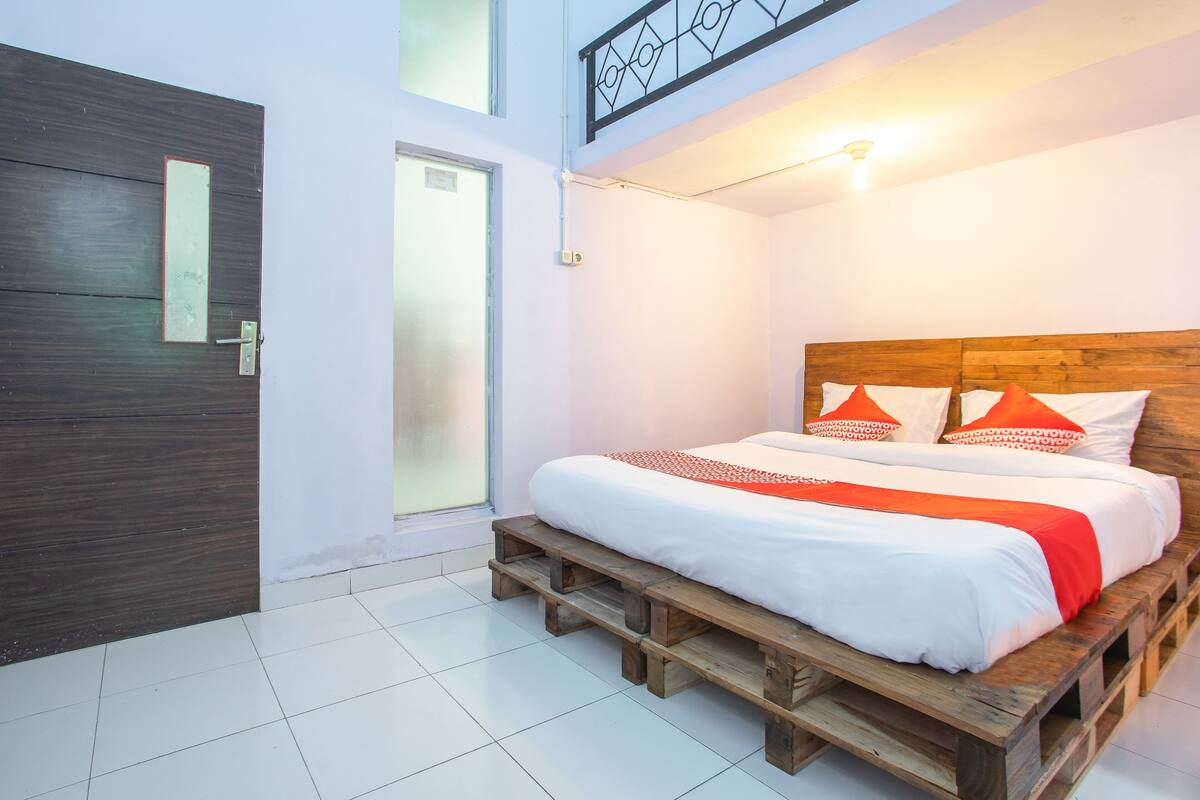 Une chambre à coucher avec un lit en bois, du linge de lit blanc et un plaid rouge.