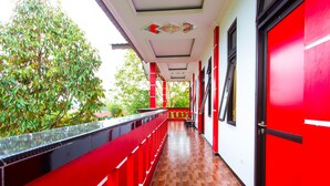 A corridor with red and white walls, a wooden floor, and a glass railing overlooking greenery. - OYO 2718 Backpacker's Homestay Jlegong (Wonosobo)