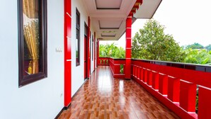 A corridor with red railings and a wooden floor, leading to a balcony with a view of greenery. - OYO 2718 Backpacker's Homestay Jlegong (Wonosobo)