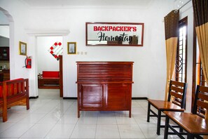 A room with a wooden bench, a red sofa, and a sign that reads "BACKPACKER'S Homestay". - OYO 2718 Backpacker's Homestay Jlegong (Wonosobo)