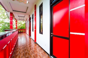 Um corredor com paredes vermelhas e brancas, chão de madeira e uma porta vermelha.