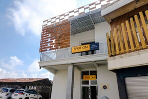 Un bâtiment avec une enseigne indiquant « SPOT ON », un balcon avec une balustrade en bois et une porte de garage.