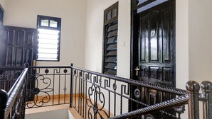Una escalera con barandales negros decorados que lleva a una puerta con un ventanal.
