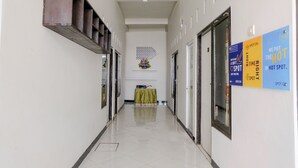 Un pasillo con tragaluz, una mesa con mantel verde y señalizaciones en la pared.