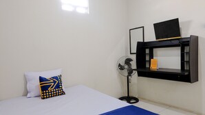 Habitación de hotel con cama, ventilador, estante con televisor y ventana.