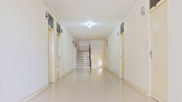 A long, narrow hallway with white walls and doors on both sides.